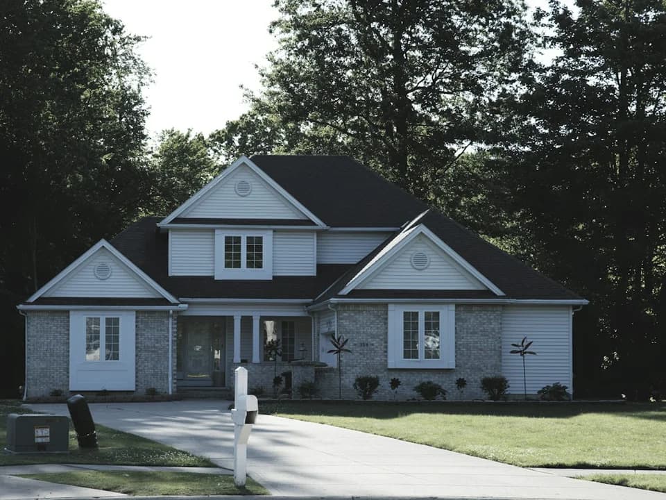 A well kept home with white siding and a green lawn
