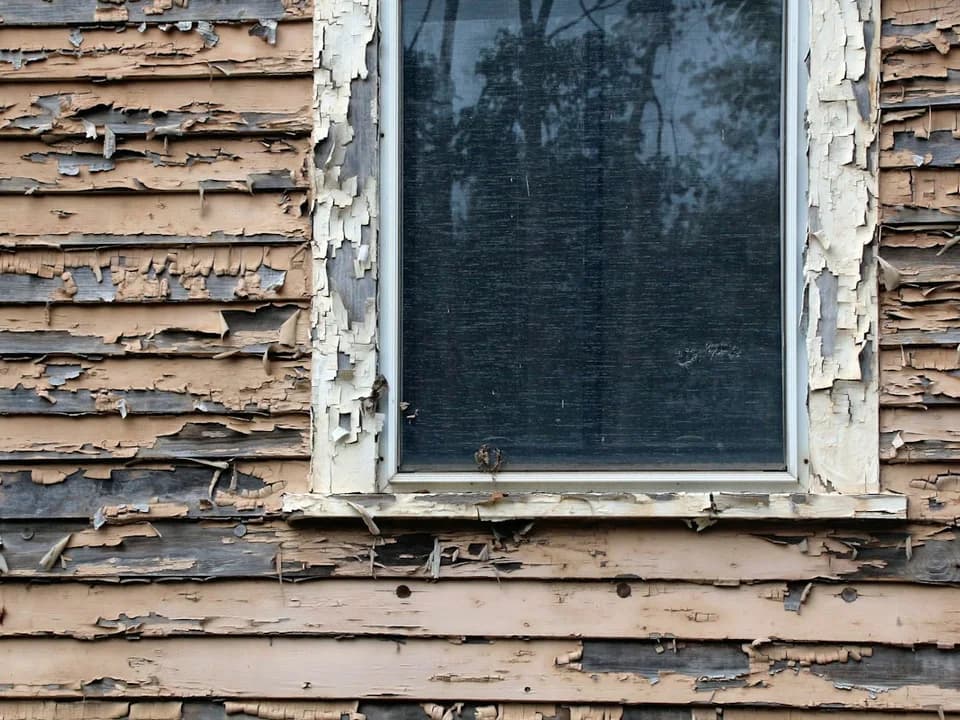 Weathered wood siding and a window with peeling paint